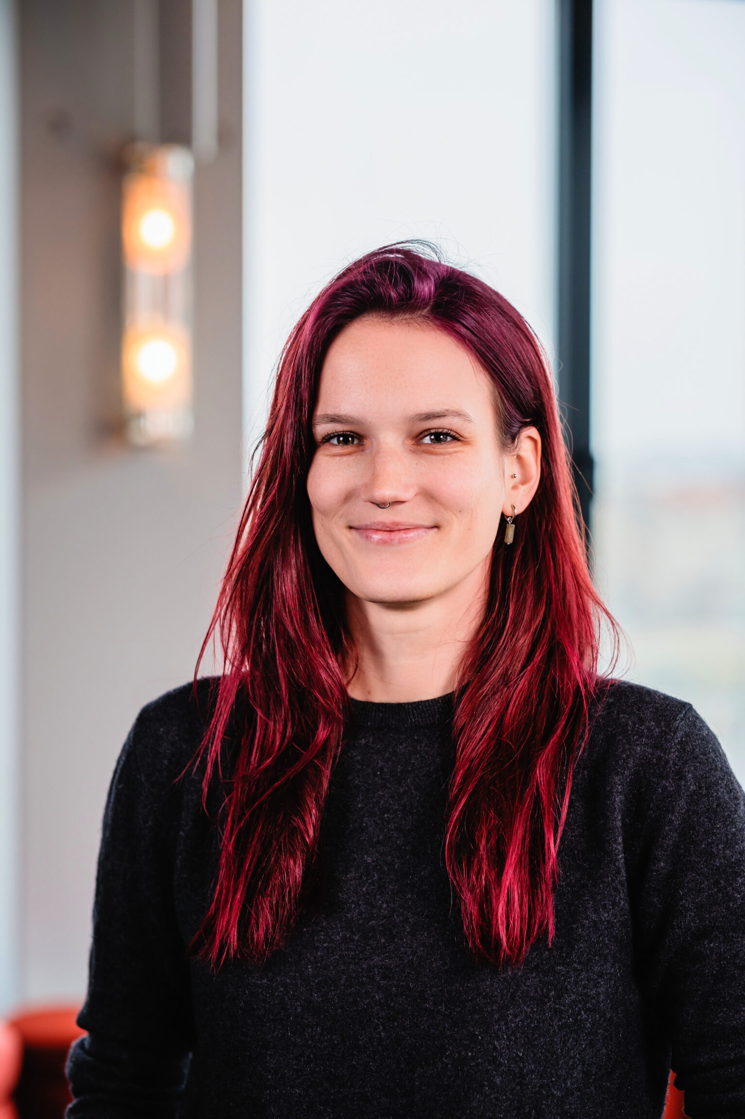 Eine weiße Frau mit langen roten Haaren lächelt in die Kamera.