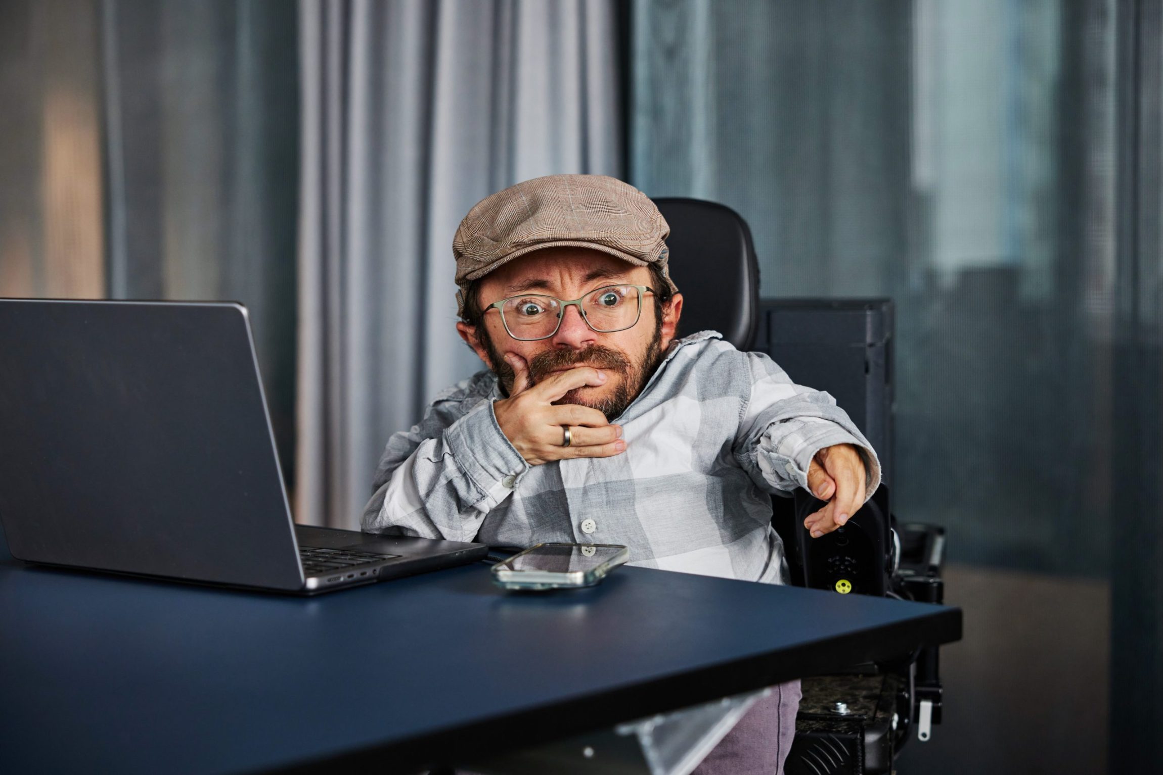 Raul Krauthausen an einem Tisch. Ein Laptop steht auf dem Tisch