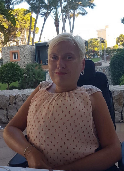 Jenny Bießmann, eine weiße Frau mit blonden, kurzen Haaren trägt eine Bluse und lächelt in die Kamera.